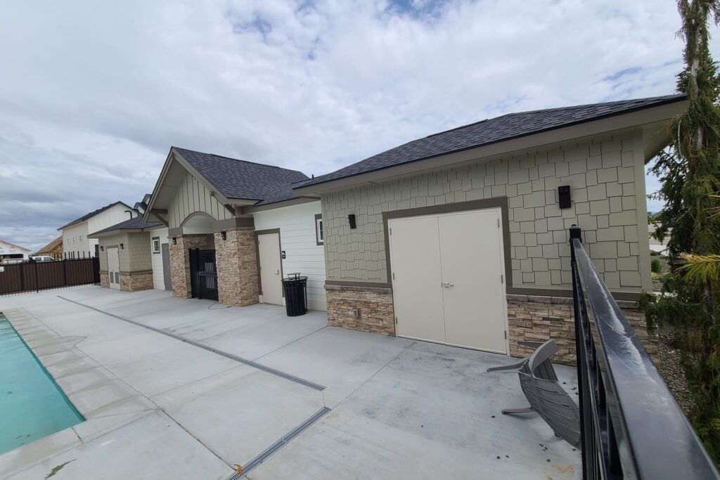 Repainted two tone commercial pool house exterior with stone accents and pool in foreground in Meridian