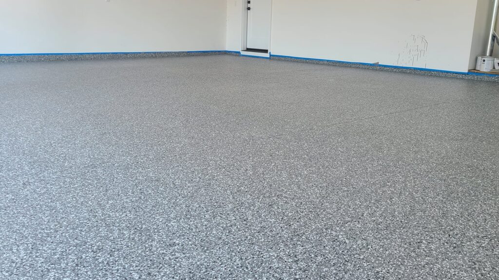 Finished light flake epoxy garage floor in a Meridian home looking out toward the single door