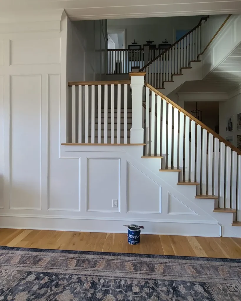 Repainted wainscoted stairwell with oak treads and white spindles in a Treasure Valley home