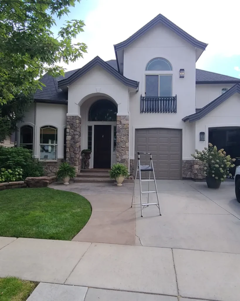 Repainted two story stucco and stone craftsman home exterior with an All Shades of Painting yard sign in Meridian, Idaho
